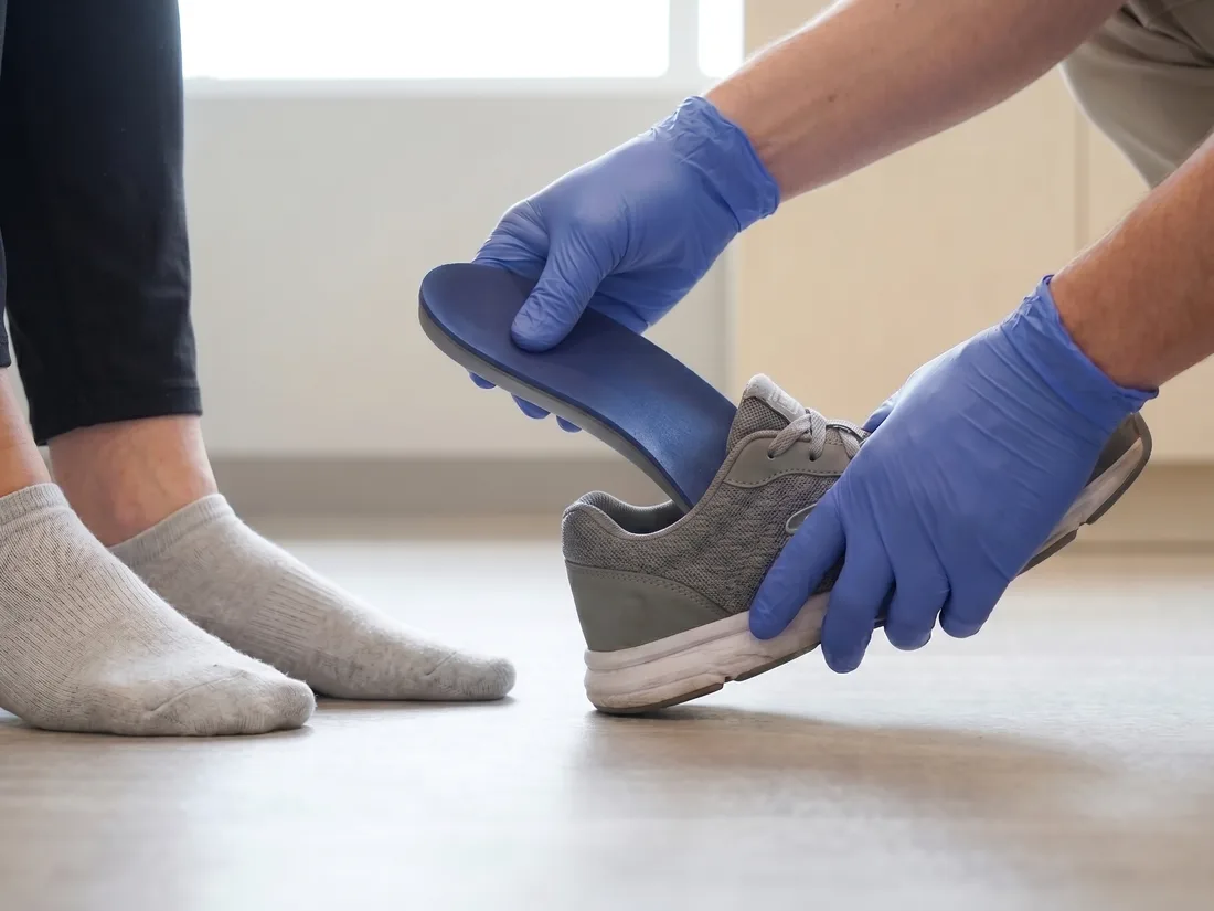 A clinician fitting a 3D-printed orthotic into a patient’s shoe